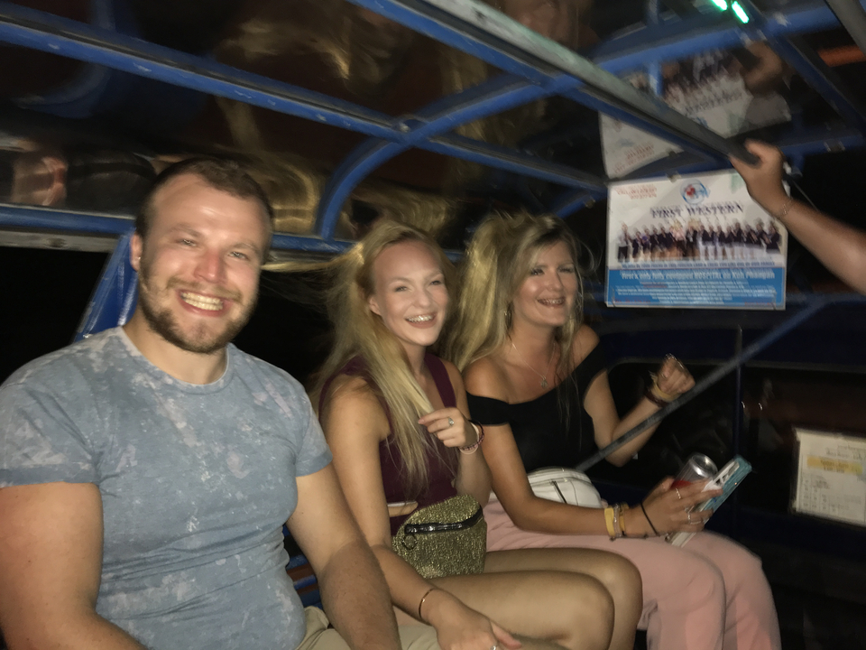 Friends laughing on a nighttime tuk-tuk ride.