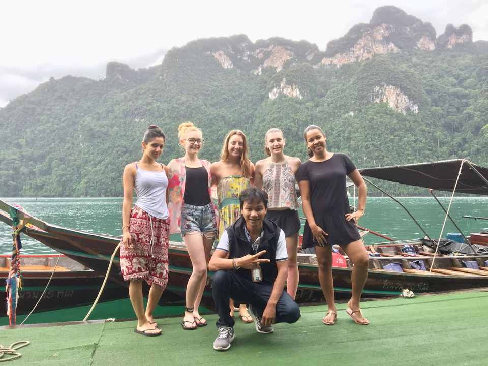 Group of friends posing on a boat with a scenic backdrop