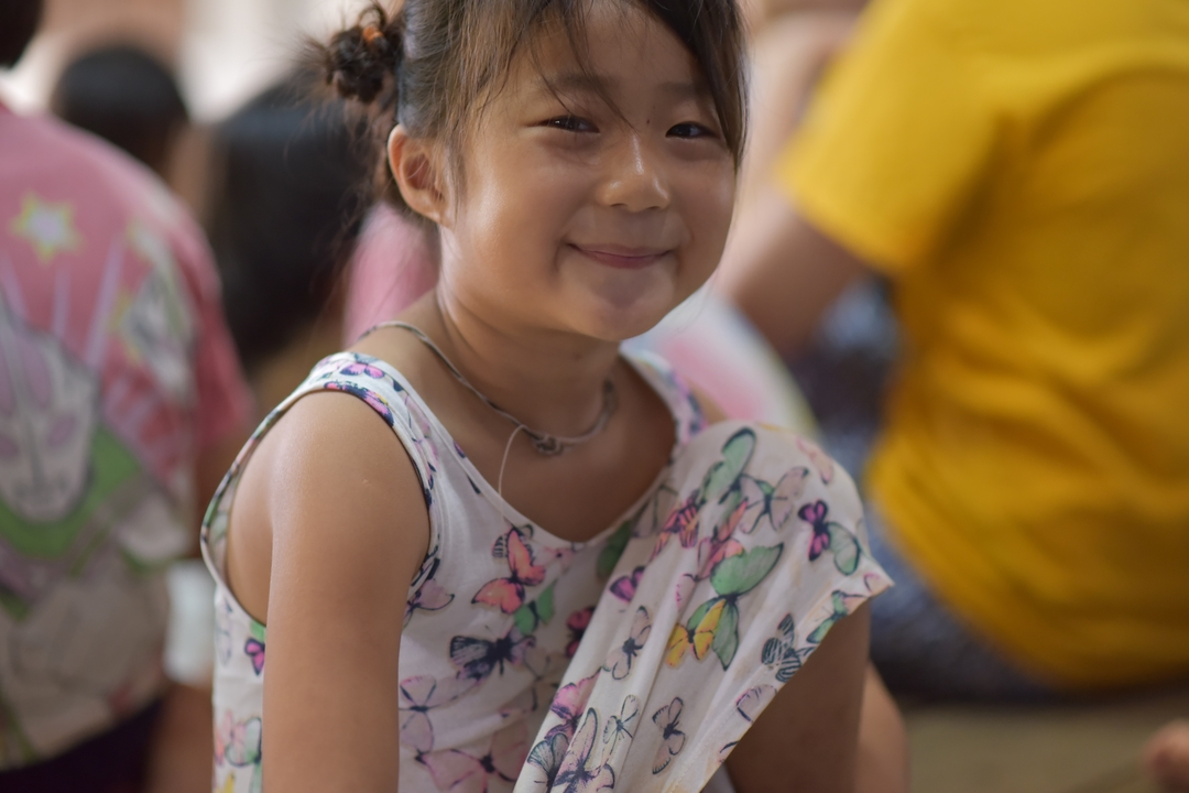 Enfant souriant assis sur le sol.