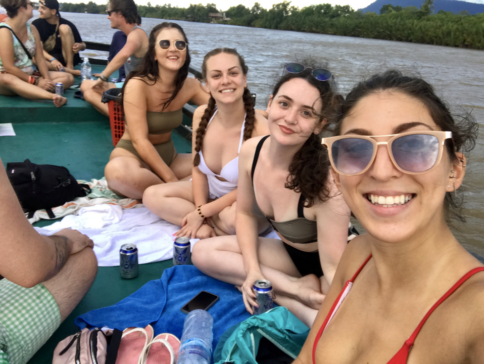 Groupe d'amis assis sur un bateau tenant des boissons