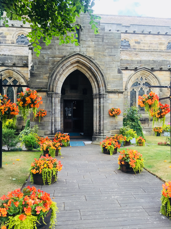 Une entrée d'église entourée d'arrangements floraux éclatants.
