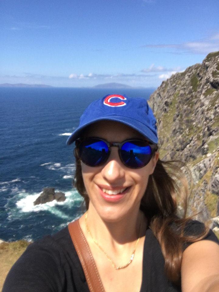 Personne qui prend un selfie avec un arrière-plan flou de falaises et d'océan.