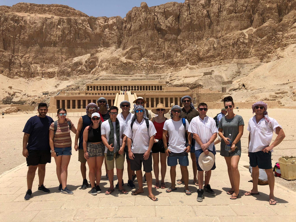 Groupe de personnes posant devant un temple égyptien dans le désert.