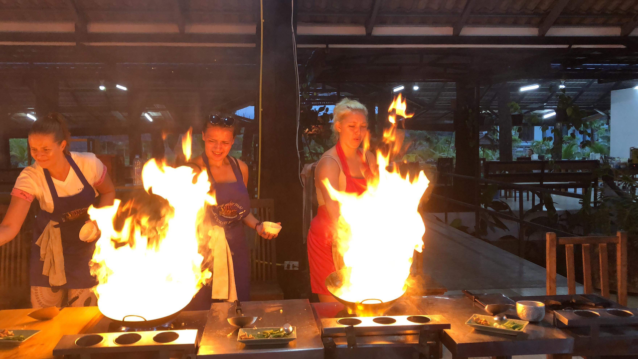 People cooking with fire flaming in the kitchen.
