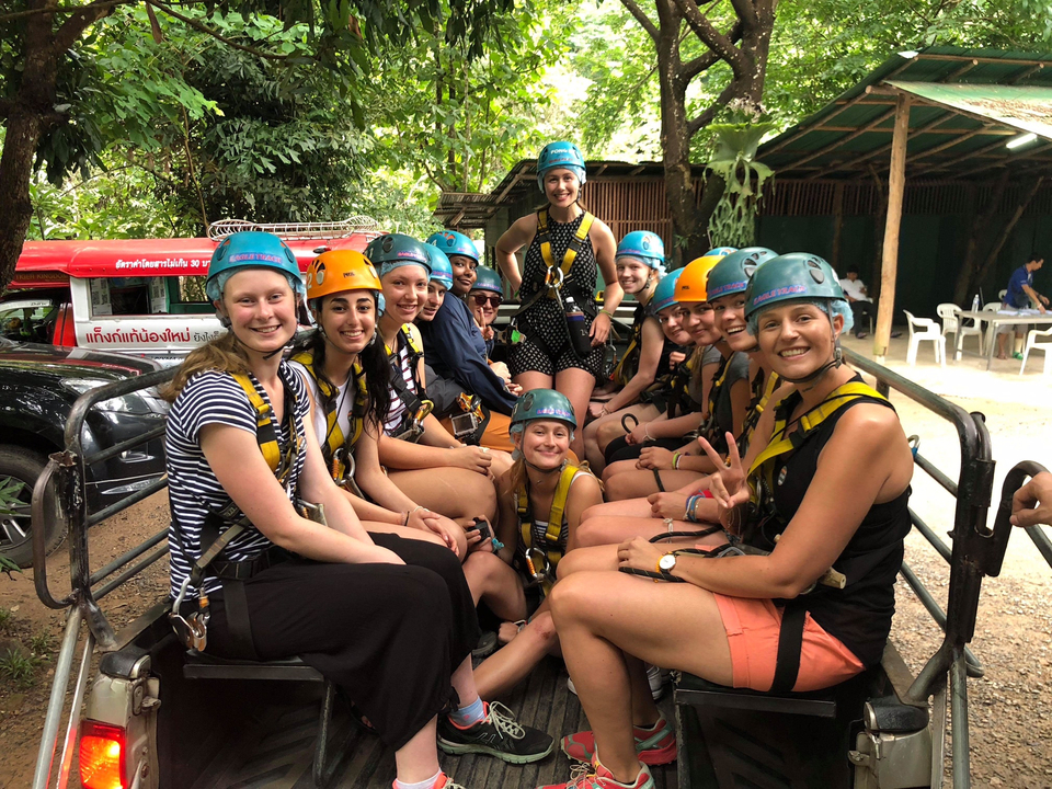 Group of people wearing helmets sitting on a truck ready for an adventure.