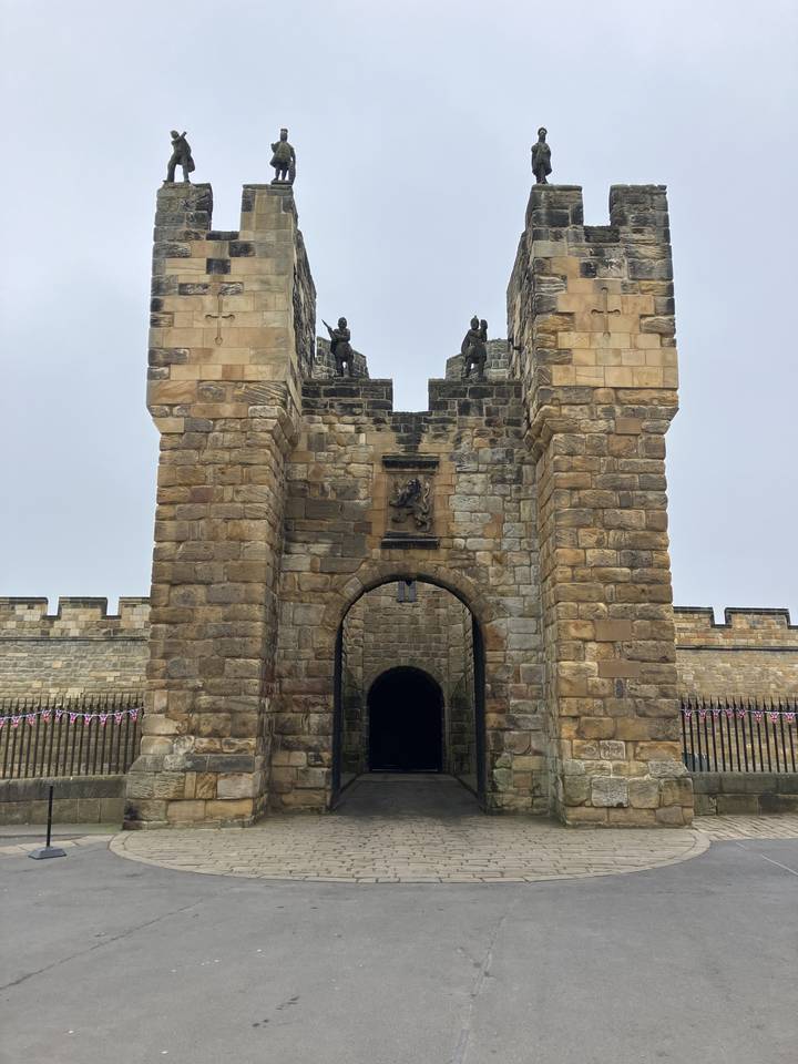 Majestuosa puerta de piedra con almenas contra un cielo gris.