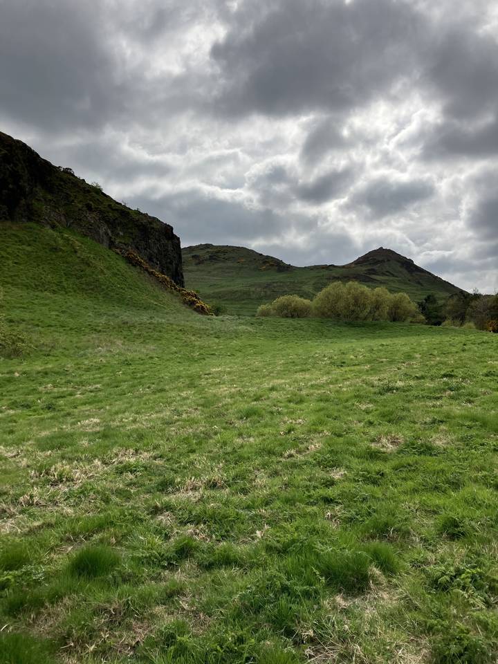 Colinas verdes ondulantes bajo un cielo nublado.