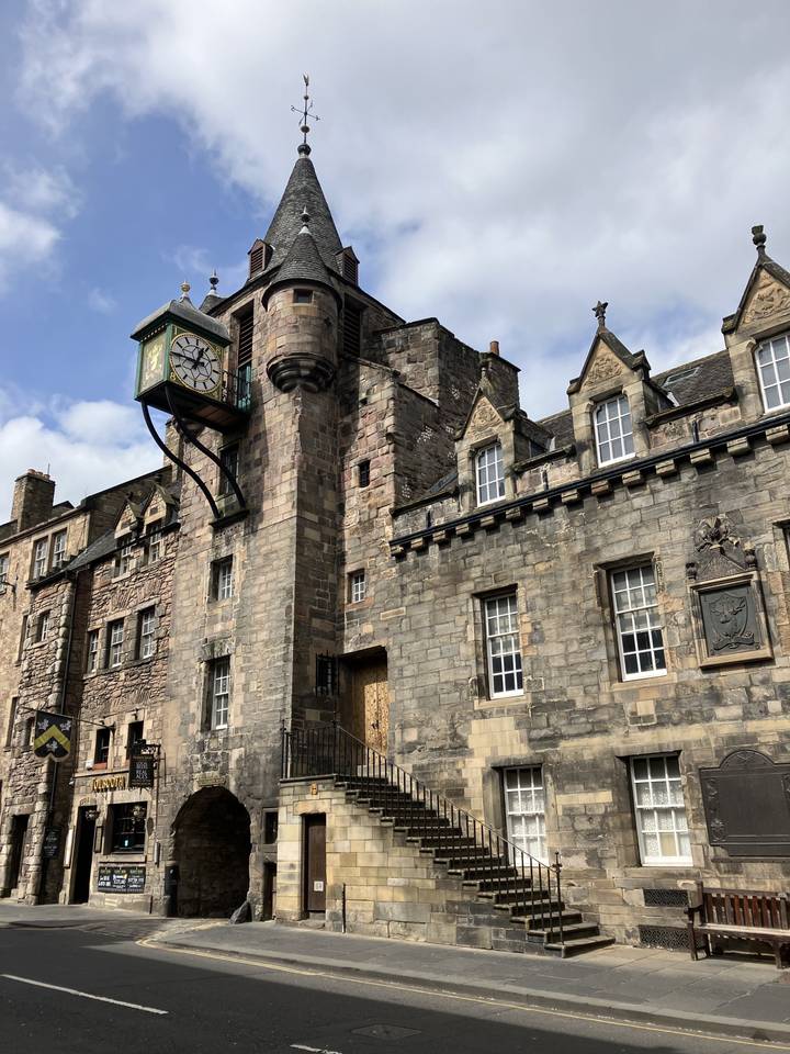 Edificio histórico de piedra con una torre de reloj prominente.