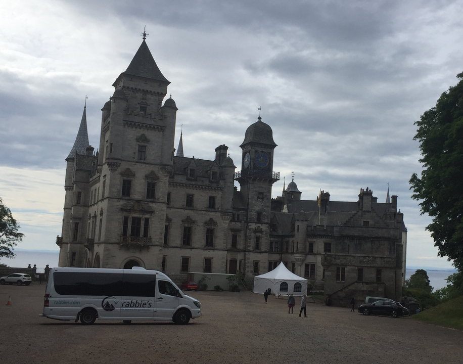 Grand château avec une camionnette garée devant et des tentes.