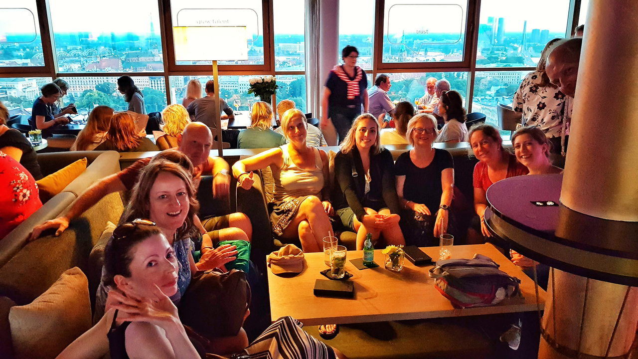 Groupe de personnes assises dans un salon avec vue sur la ville depuis les fenêtres.