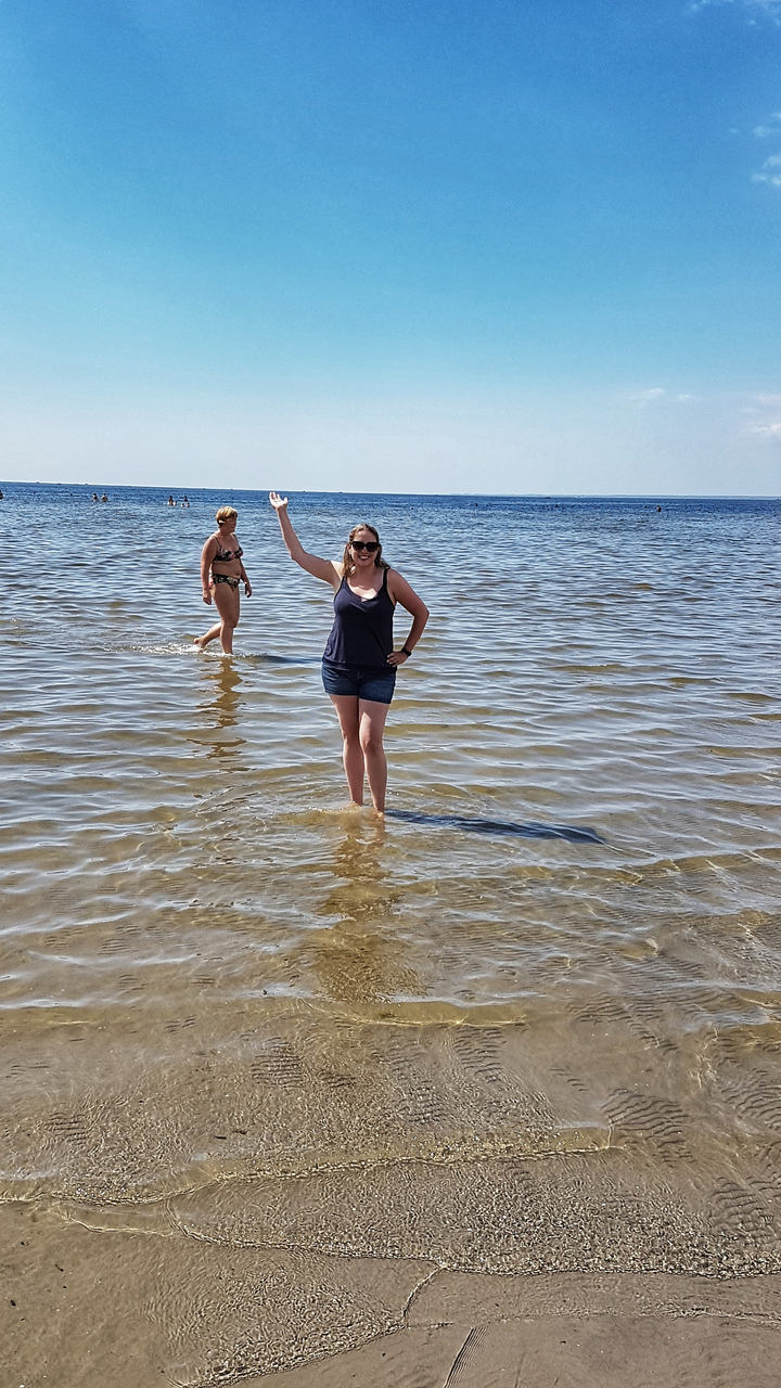 Deux personnes debout dans l'eau de mer peu profonde, profitant de la plage.