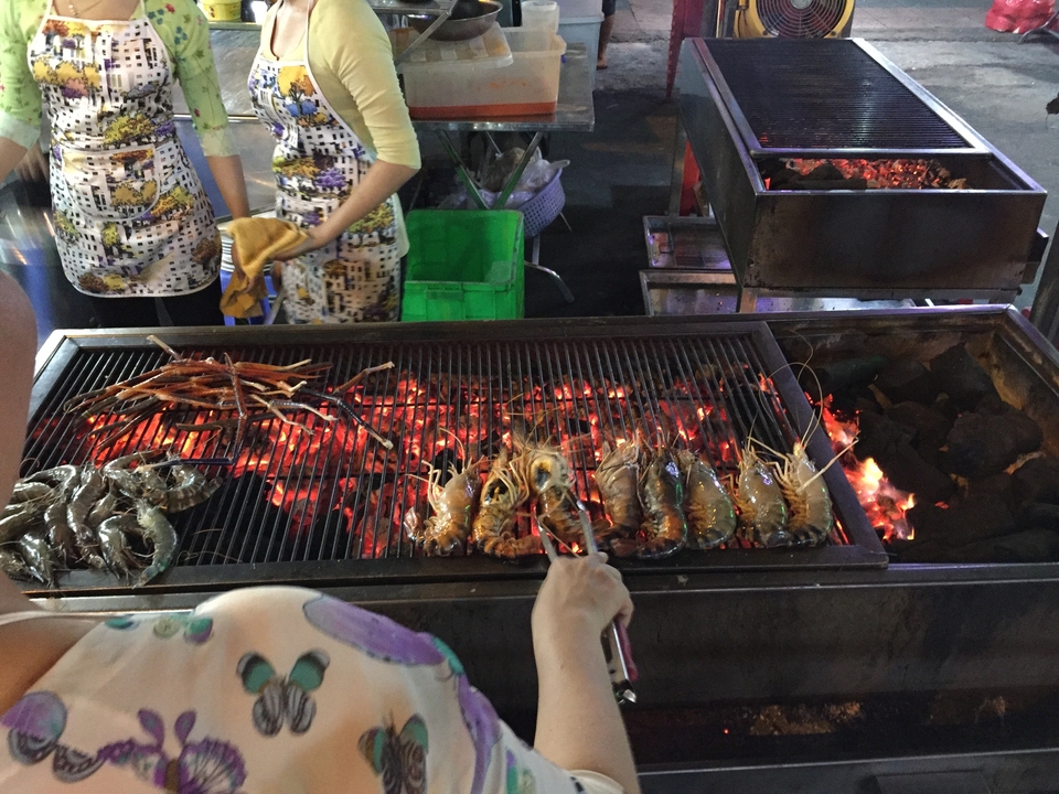 Des gens qui grillent des fruits de mer sur des flammes nues.