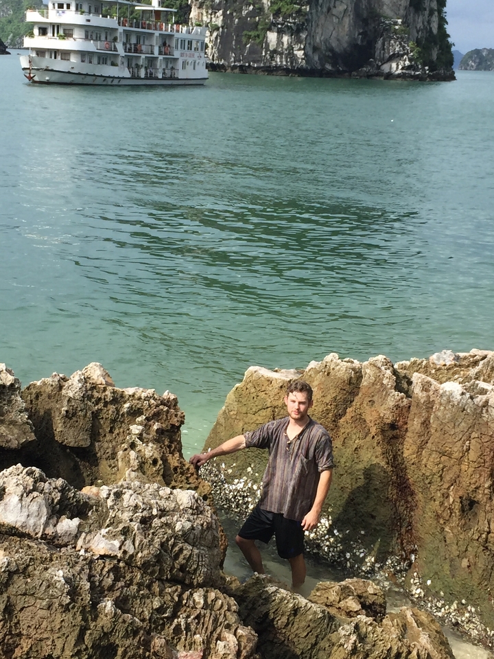 Personne debout entre des rochers avec de l'eau en arrière-plan.