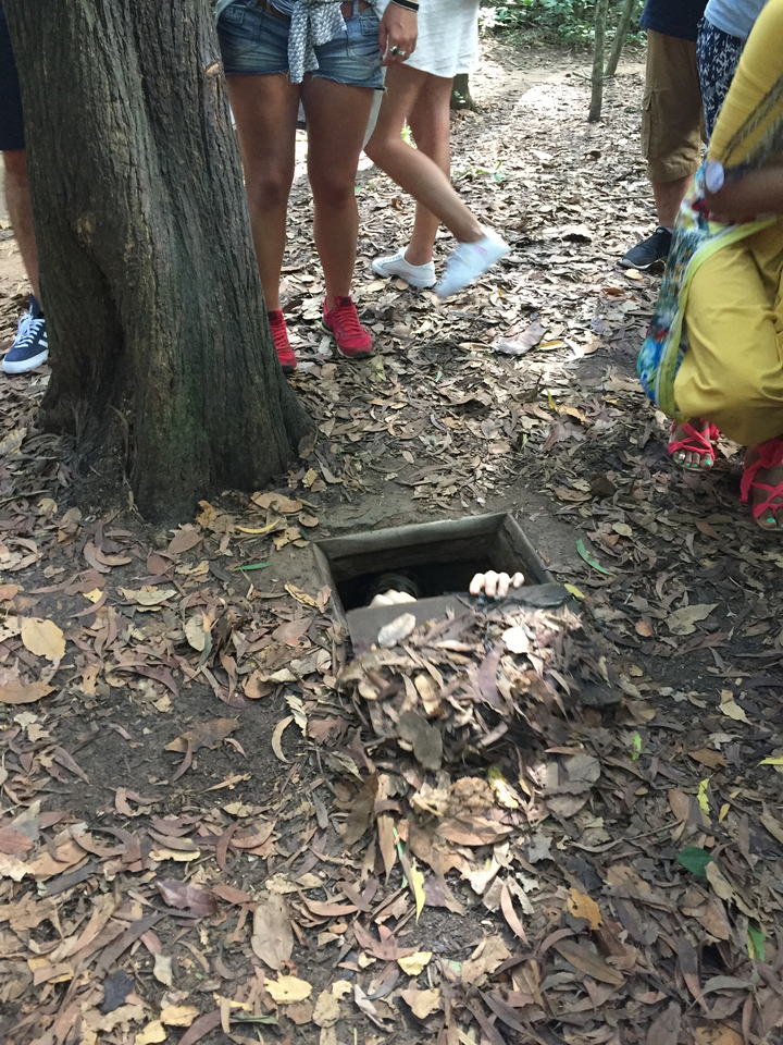 Personne émergeant d'une trappe dans le sol.