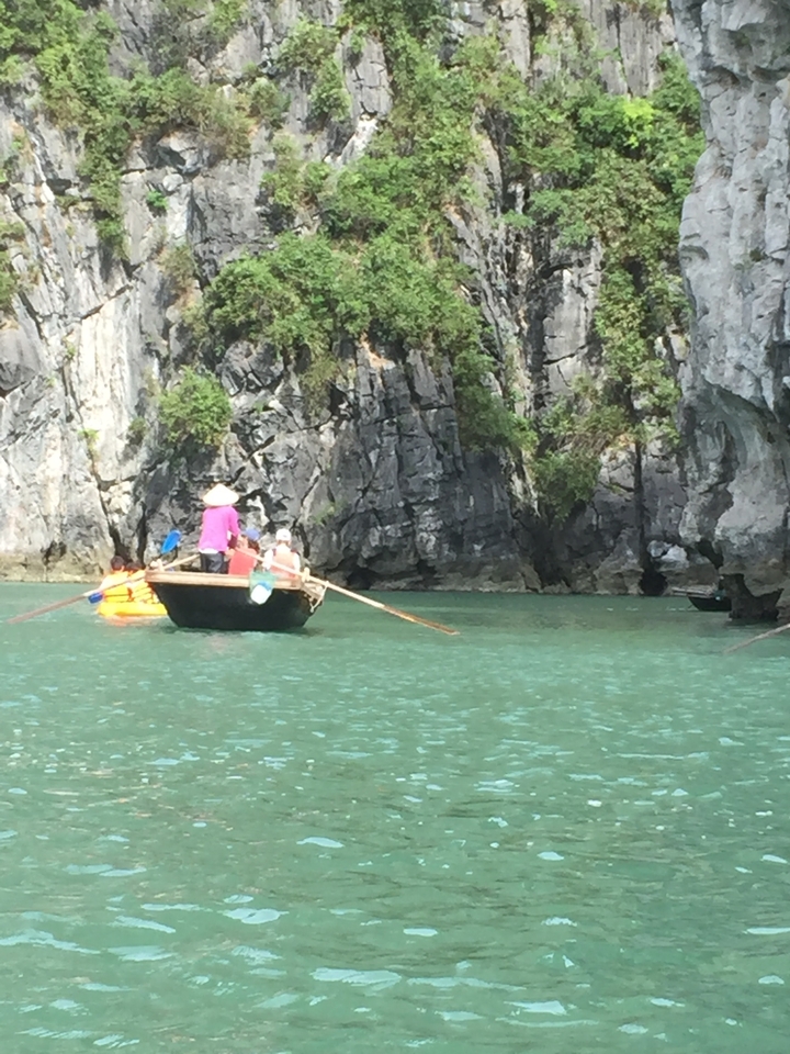 Touristes ramant en bateau près de falaises calcaires.