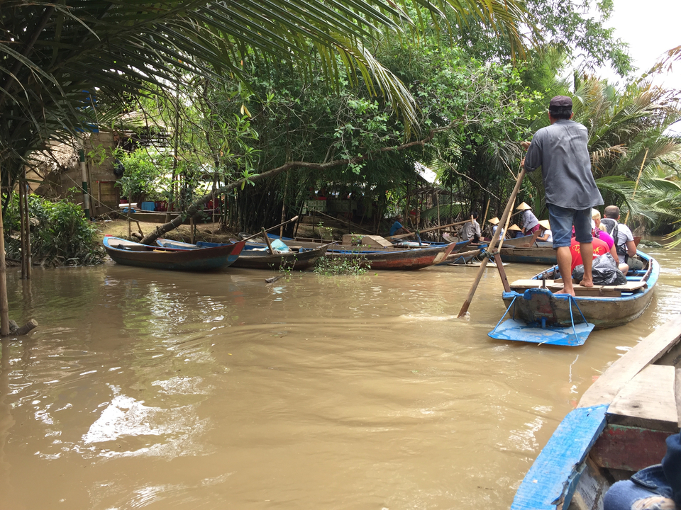 Des bateaux transportant des touristes le long d'une rivière boueuse.