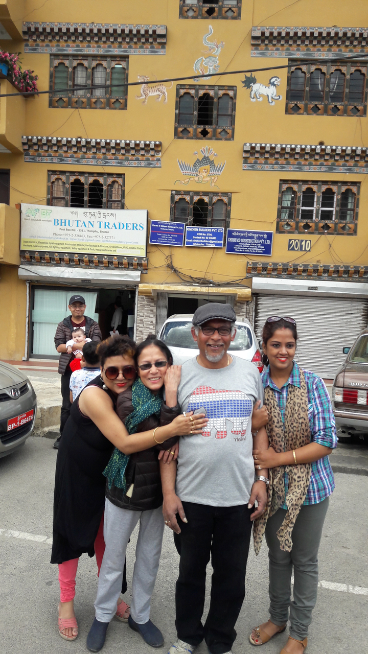 Groupe de personnes posant avec des bâtiments en arrière-plan.