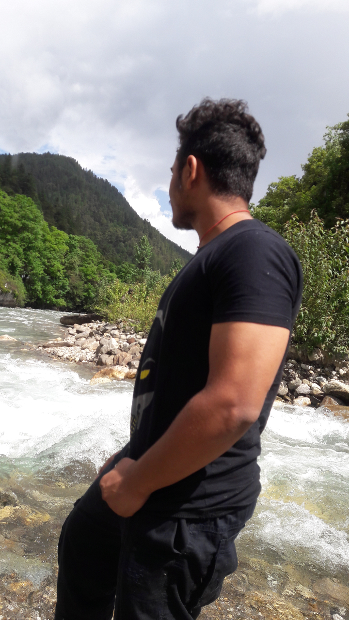 Personne debout près d'une rivière avec de la verdure autour.
