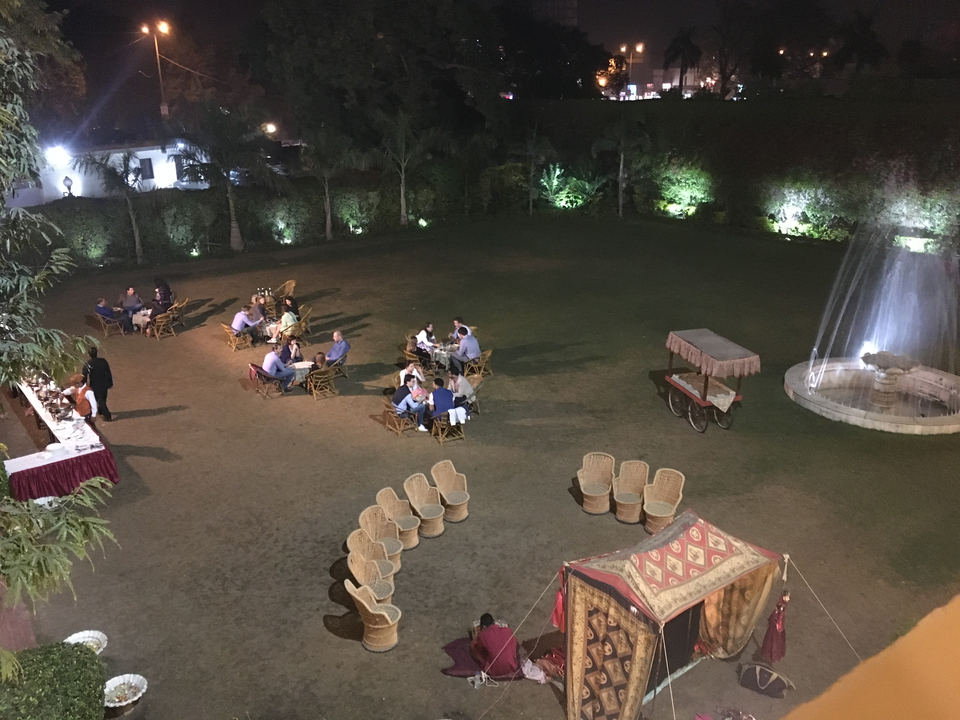Scène de dîner en plein air le soir avec des invités assis autour des tables.