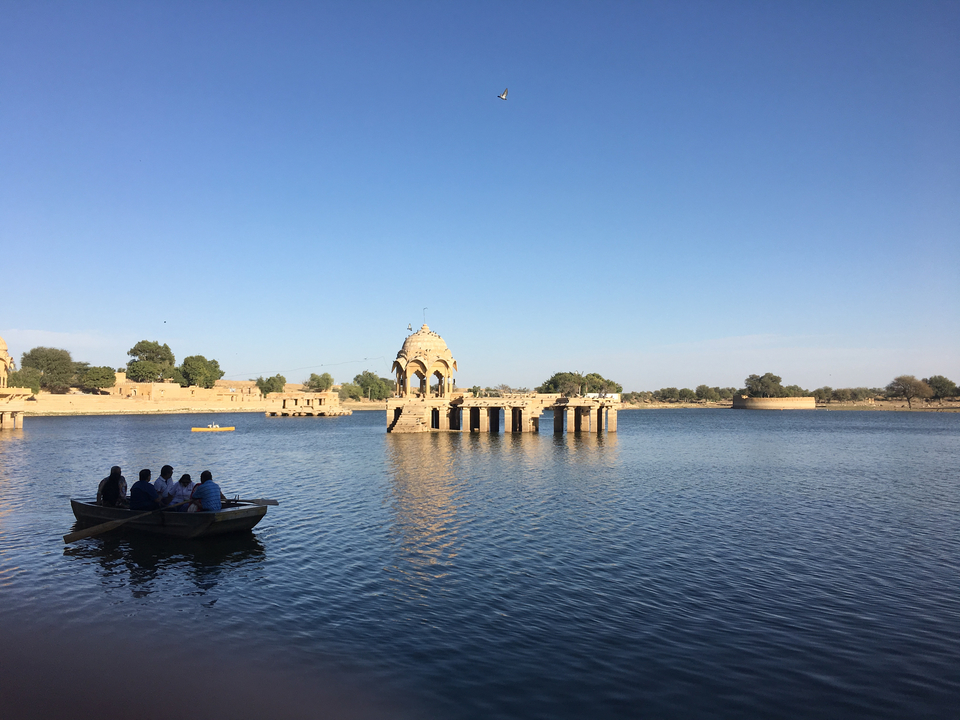 A picturesque lake with architectural ruins and people in a boat.