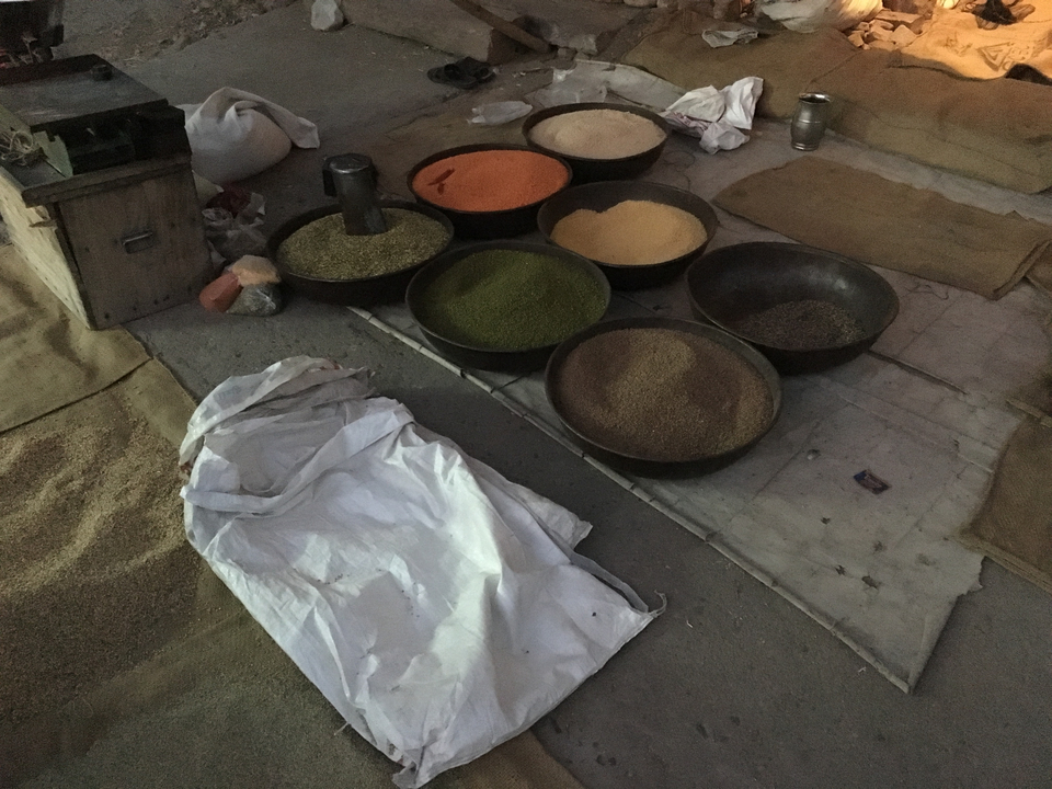 Céréales et légumineuses exposées dans des bols sur le sol d'un marché.