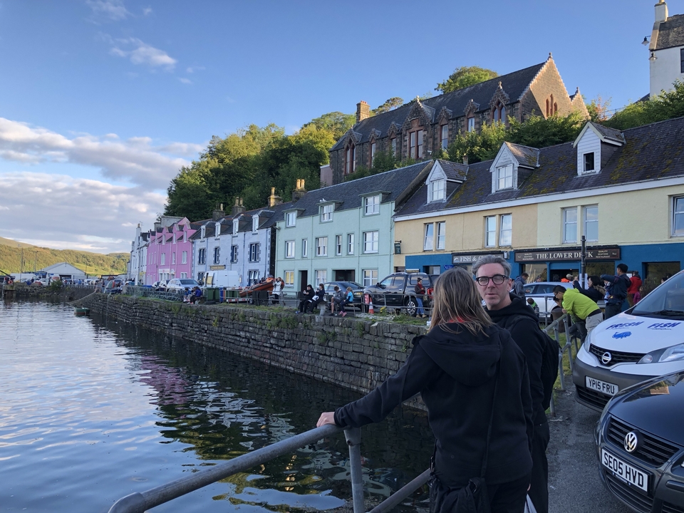 Bâtiments colorés au bord de l'eau avec des bateaux et des gens.