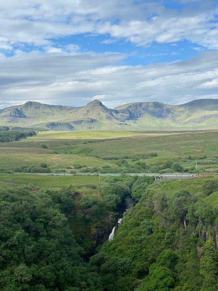 Mountainous landscape with a bridge and lush green terrain.