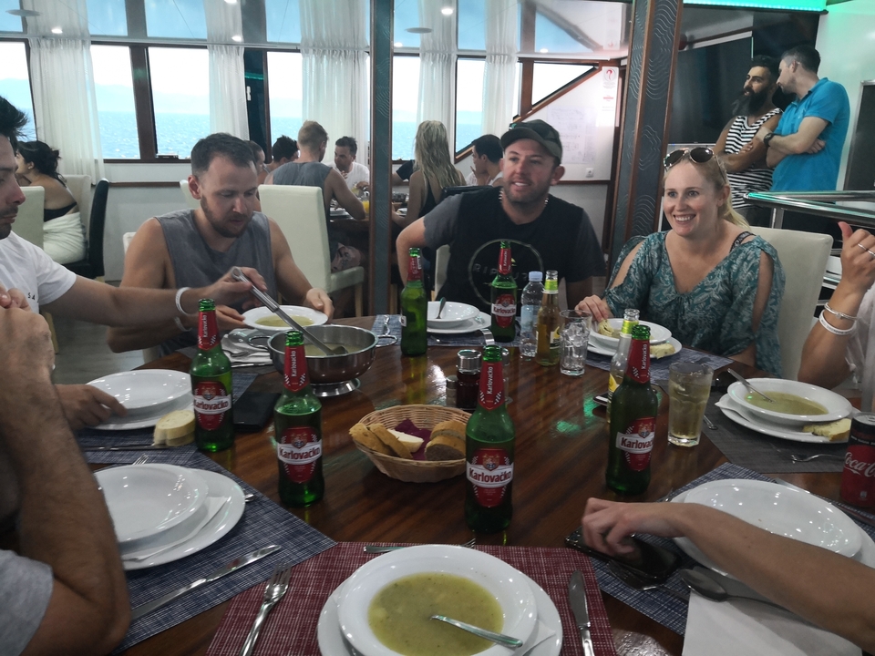 Groupe de personnes assises autour d'une table avec de la nourriture et des boissons dans un restaurant.