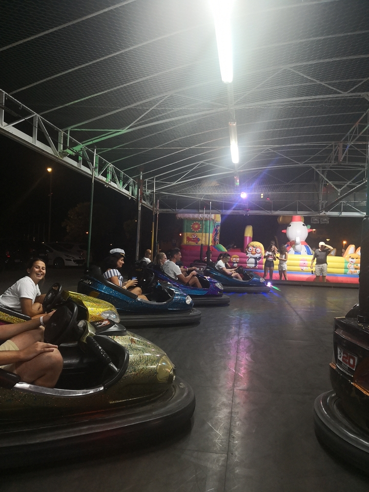 Des gens qui conduisent des autos tamponneuses dans un parc d'attractions couvert.