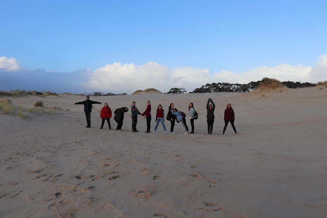 Ligne de personnes posant sur une plage de sable.