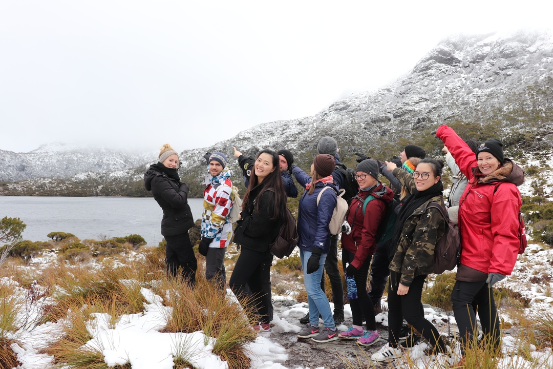 Groupe de personnes avec un paysage de montagnes enneigées en arrière-plan.