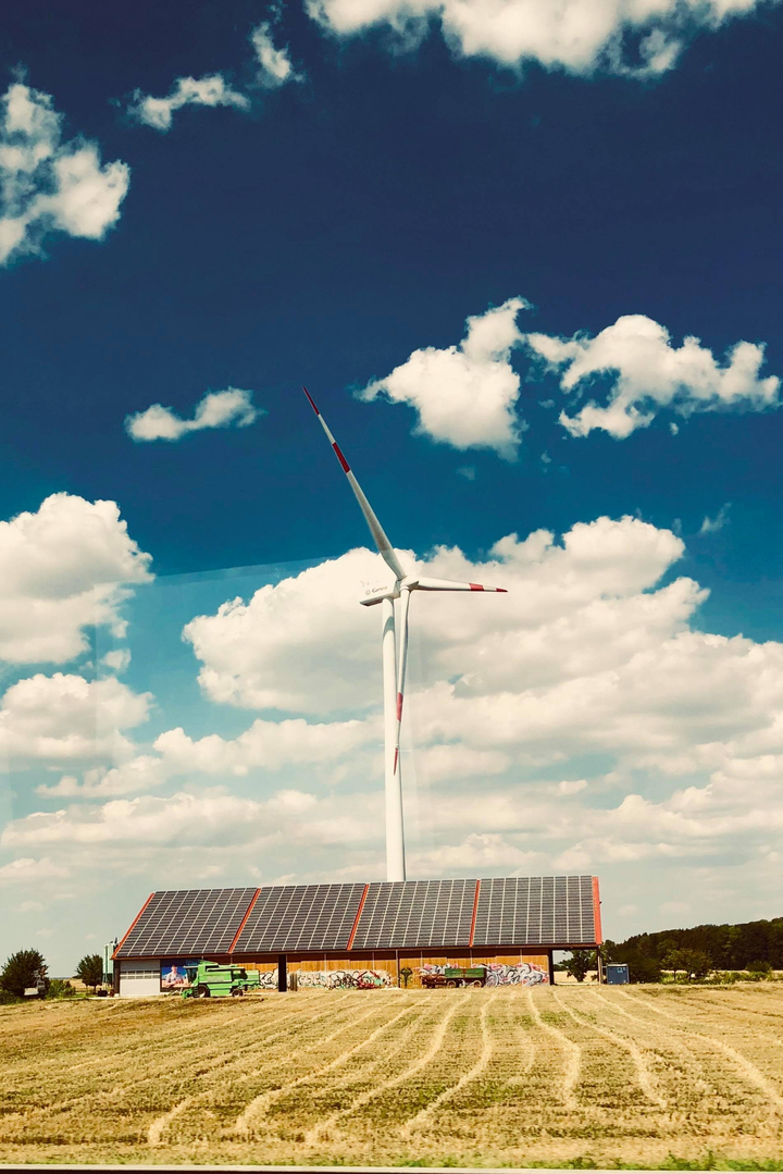 Éolienne se détachant sur un ciel bleu avec des nuages cotonneux.