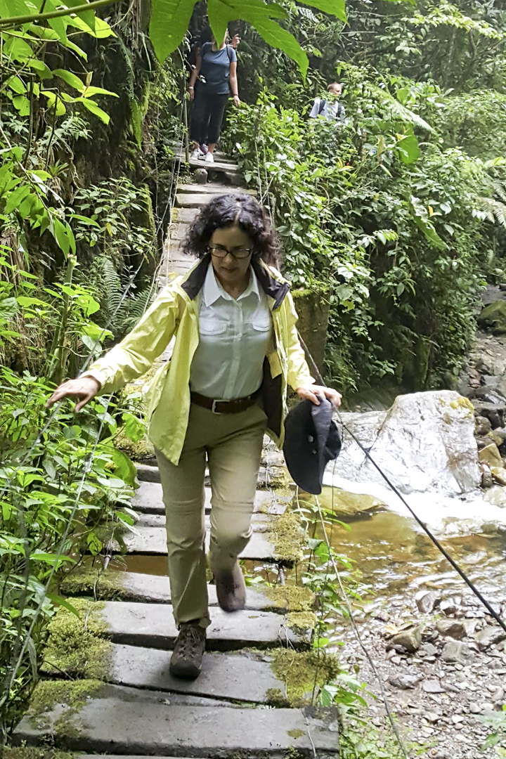Une femme faisant de la randonnée à travers une zone dense et verte.