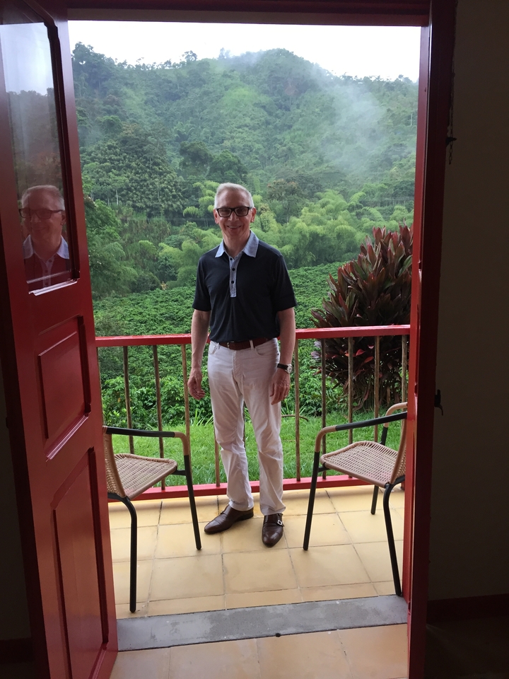 Un homme debout sur un balcon surplombant une végétation luxuriante.