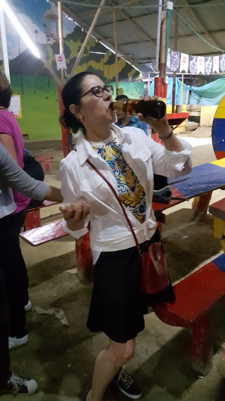 Une personne en chemise colorée tenant des objets près d'une table de pique-nique.