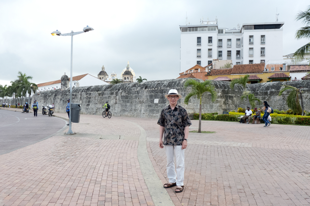 Un homme debout près d'un grand mur et d'un bâtiment.