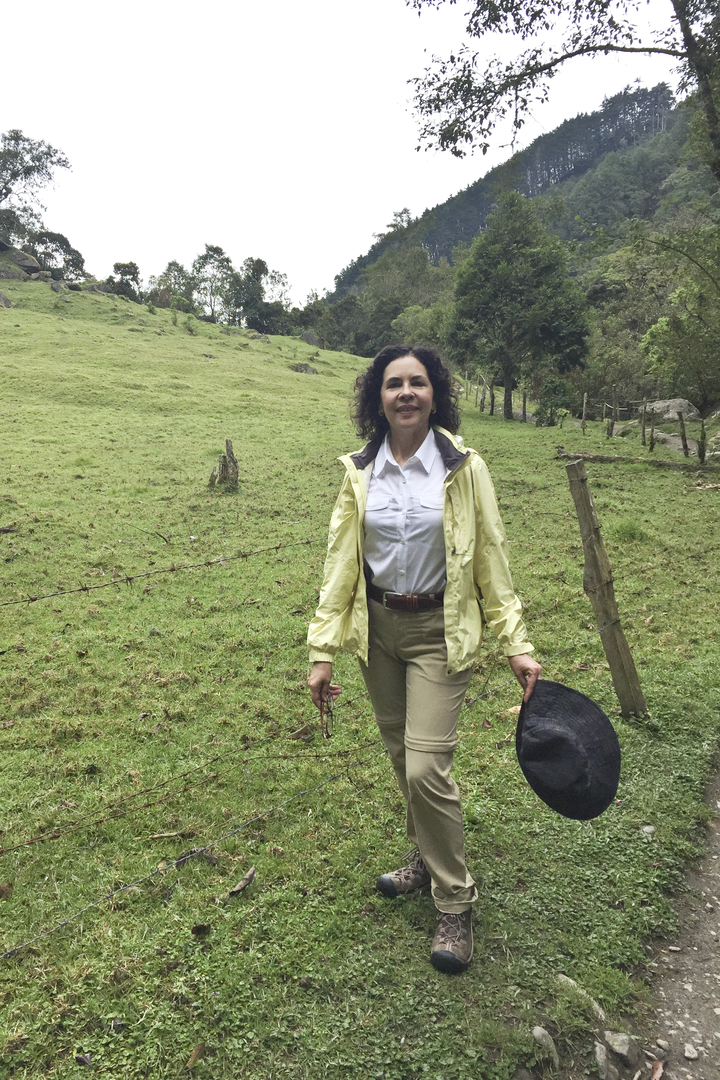 Une femme qui marche dans un champ en tenant un chapeau.