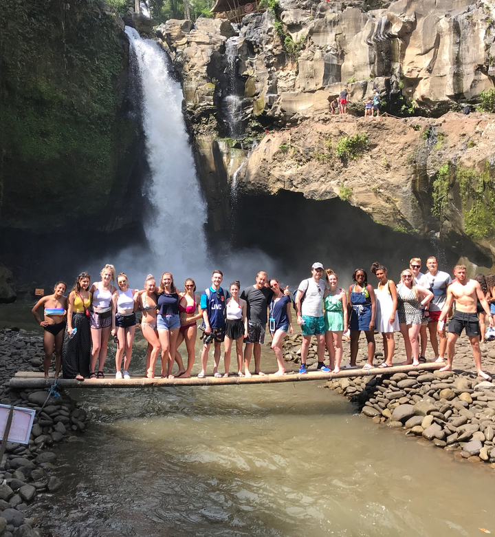 Group of people standing in front of a waterfall.