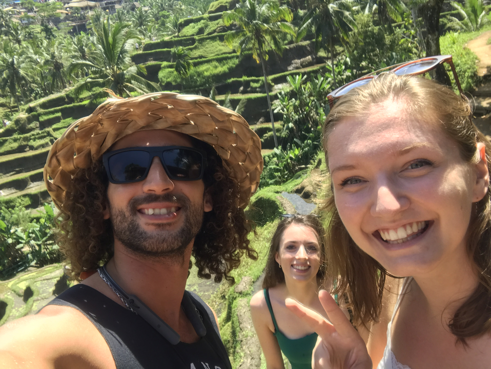 Three people posing in front of rice terraces.