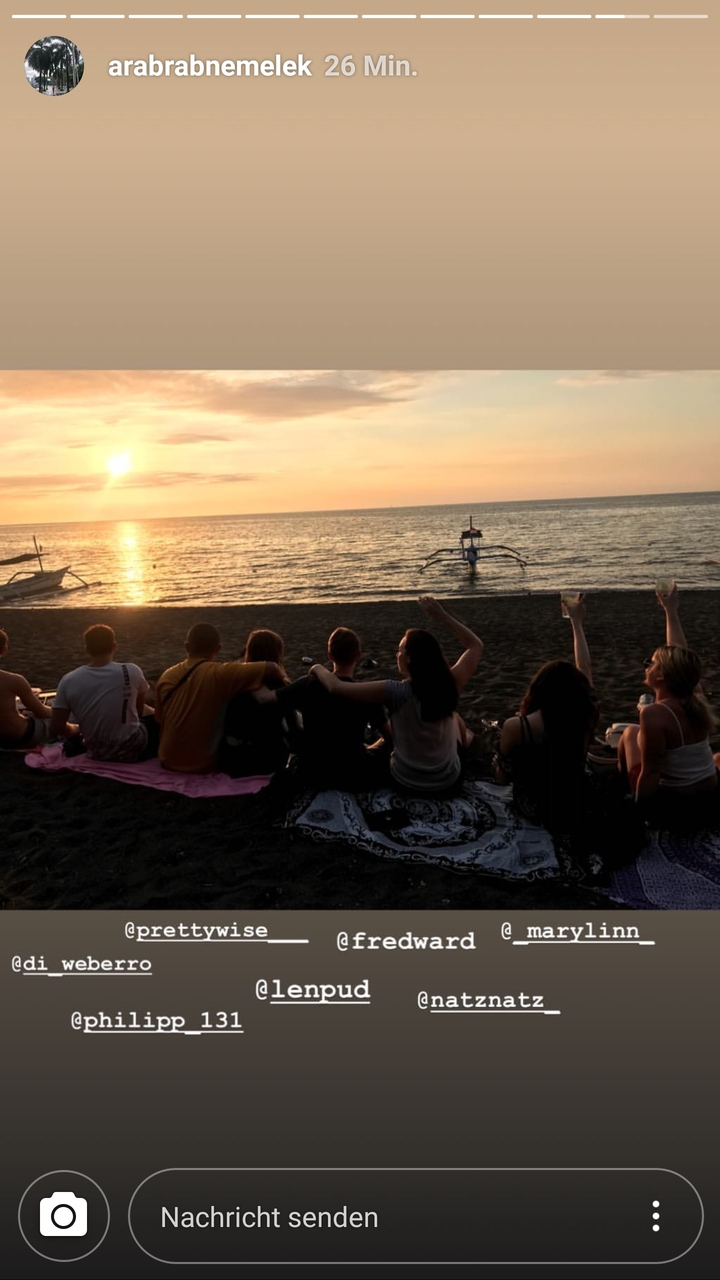 Groupe assis sur une plage regardant le coucher de soleil.