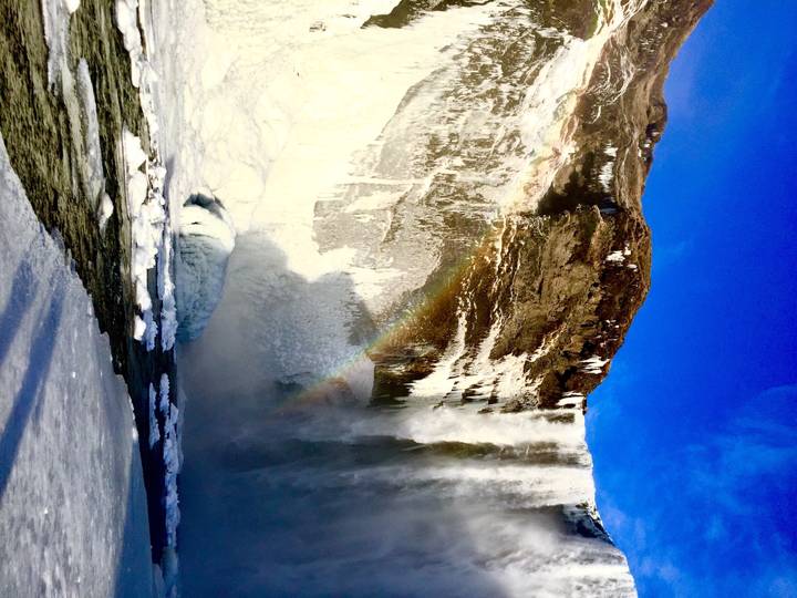 Cascade avec de la glace et un arc-en-ciel.