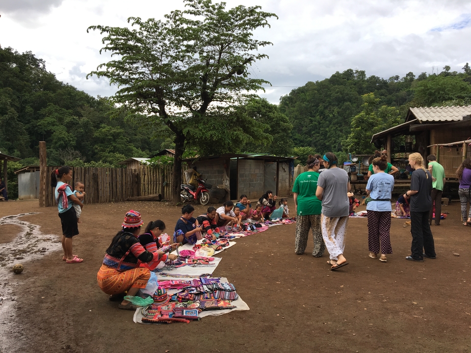 Femmes exposant de l'artisanat au sol dans une communauté villageoise rurale.