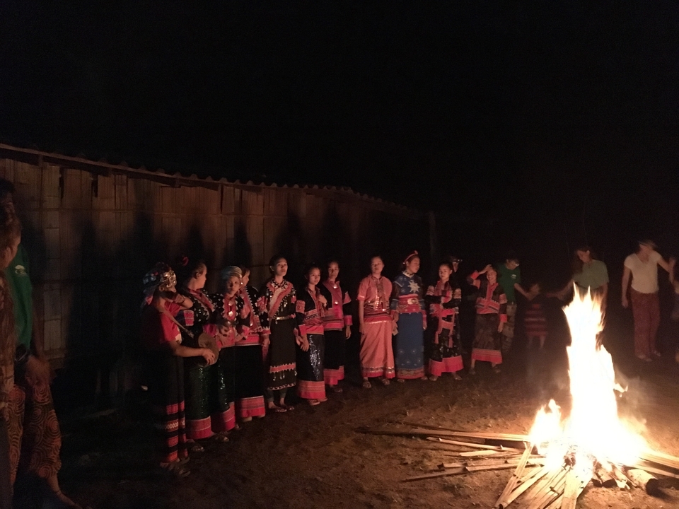 Des personnes en tenue traditionnelle se tenant autour d'un feu la nuit.