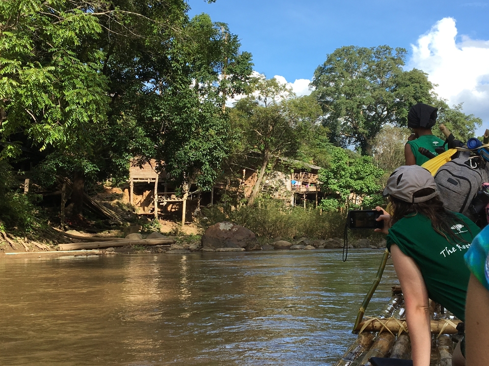 Des personnes faisant du rafting sur une rivière avec vue sur des maisons en bois sur la berge.