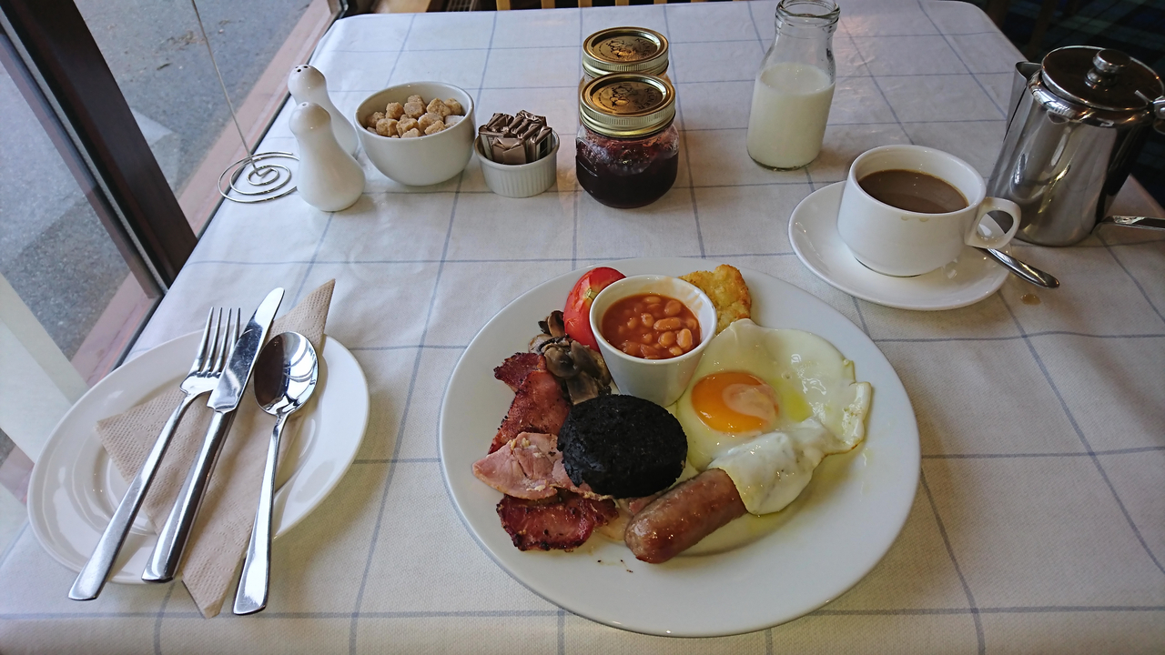 Une assiette de petit-déjeuner traditionnel complet avec des œufs, du bacon, des haricots et du pain grillé.