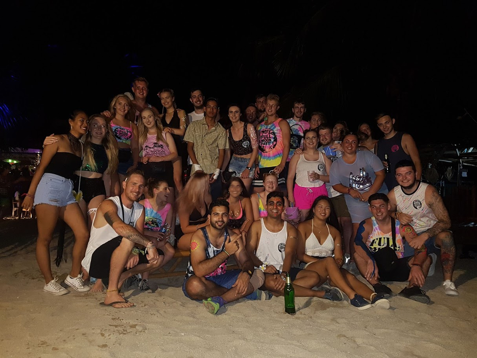 A group of people partying at night, wearing colorful outfits.