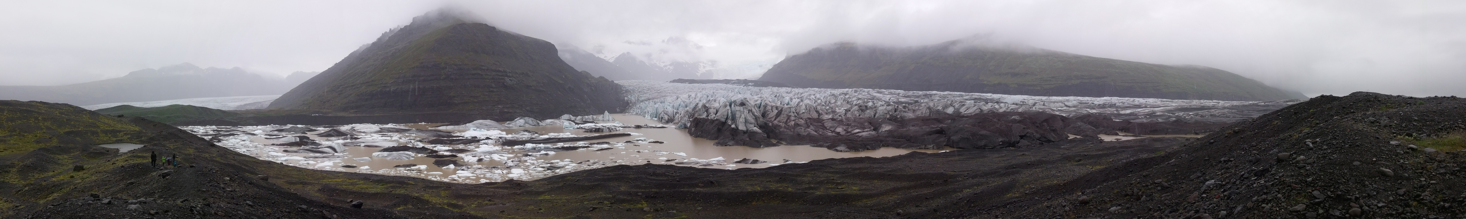 Un glacier entouré de montagnes et de terrain rocheux.