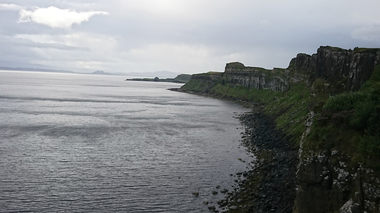 Un paysage côtier escarpé avec des falaises abruptes et une mer calme.