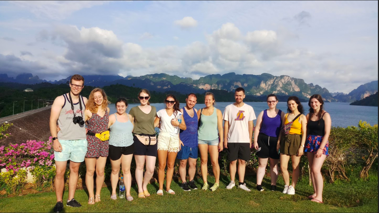 Group of people standing together with mountains in the background.