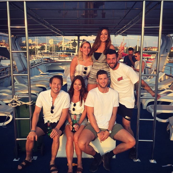 Des personnes qui posent sur le pont d'un bateau avec un paysage urbain en arrière-plan.